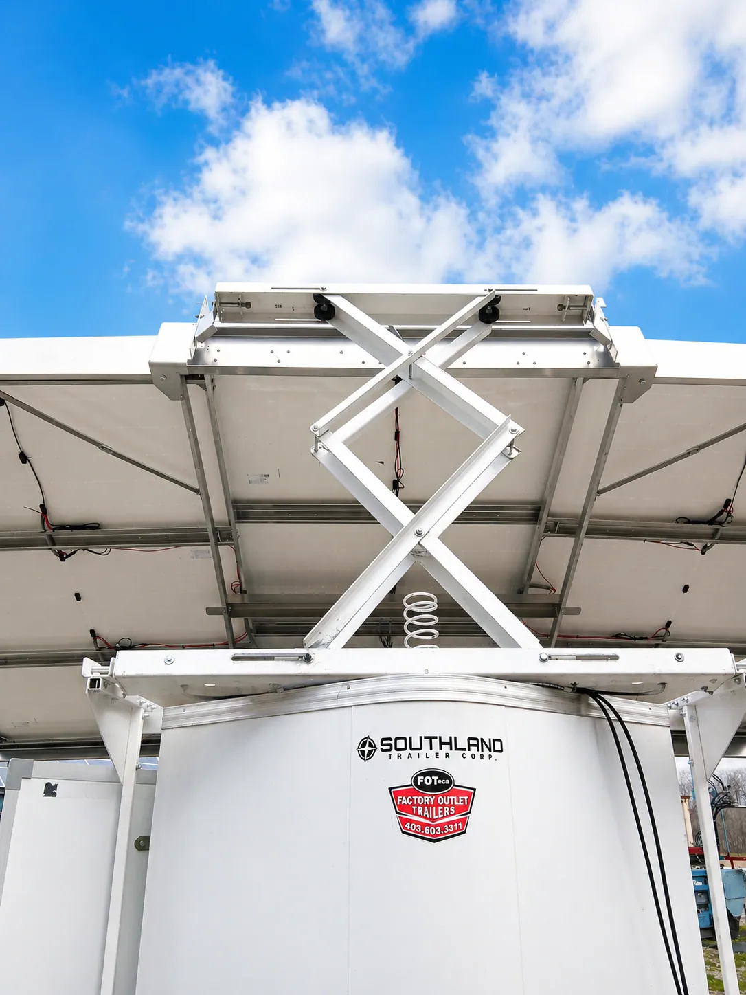 Scissor-lift hoist raising a solar array on top of an Insula trailer